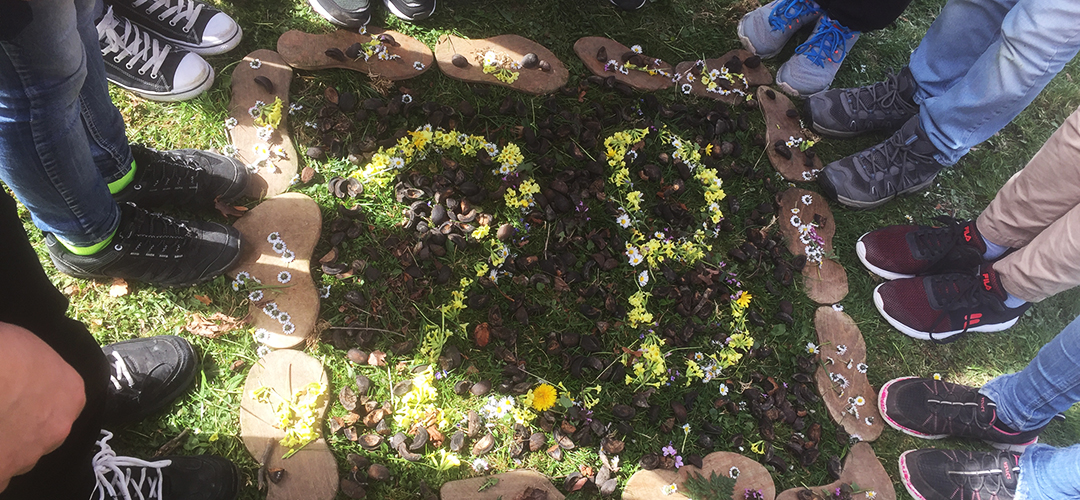 Kinder umringen blumige Land-Art